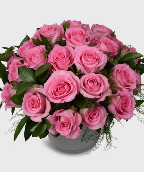 Pink roses designed in a short white cylinder with a assorted greenery-Two dozen pink roses shown