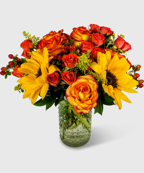 A vase filled with sunflowers, orange spray roses and orange roses