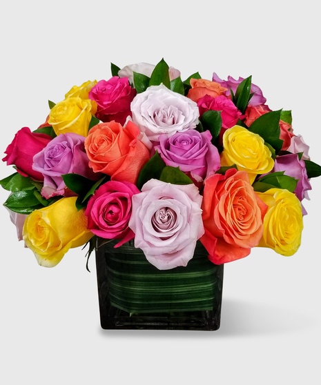  Assorted roses designed in a short leaf-lined block vase with a assorted greenery-Two dozen shown