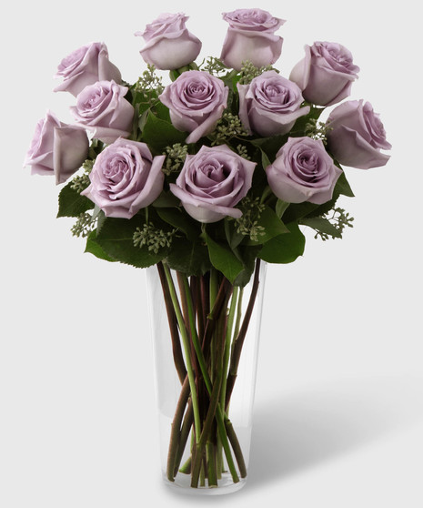 Long stem purple roses and seeded eucalyptus in a stylish glass vase.