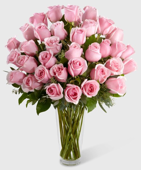 Pink roses and greenery in a clear glass vase.