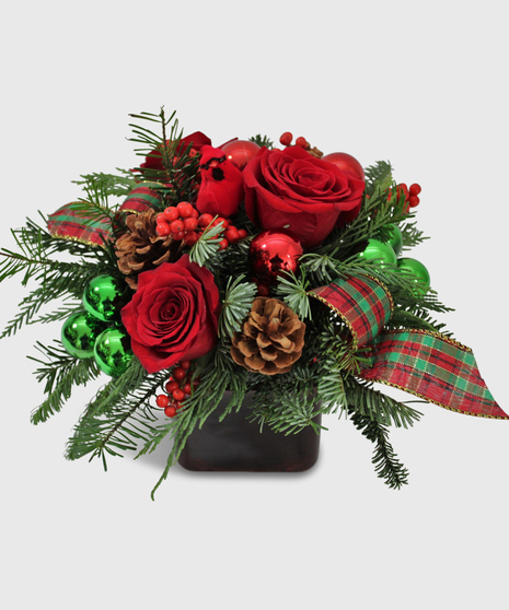 Red roses with green and red decorations designed in a red cube vase