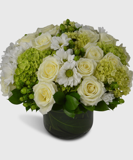 Green and white flowers arranged in a leaf-lined cylinder vase