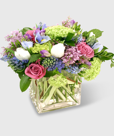 Blue, purple and green florals in a clear glass block vase.