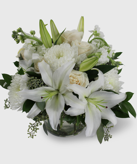 Bouquet of all white flowers designed in a short cylinder vase.