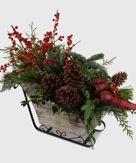 Red berries, pine cones, winter greens and decorations displayed in a sleigh