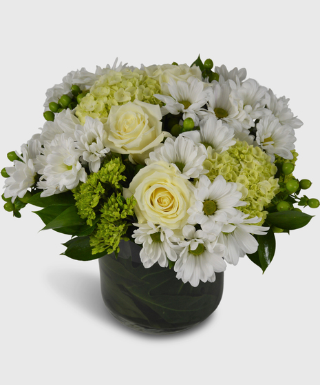 Green and white flowers arranged in a leaf-lined cylinder vase