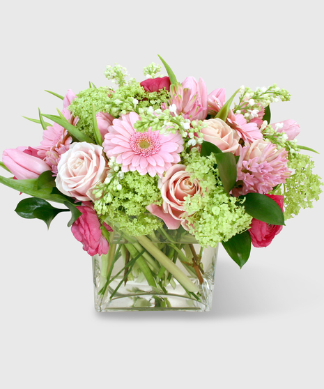 Pink and green florals designed in a clear glass block vase.