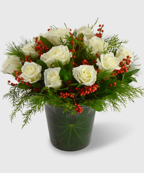 White roses, ilex berries and winter greens designed in a leaf-lined vase